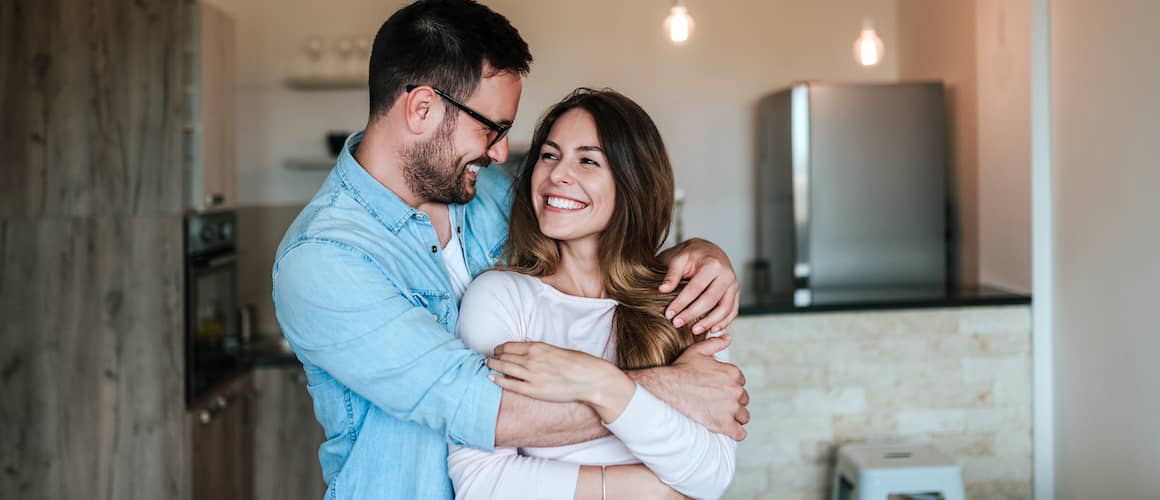 Happy young couple embracing comfortably in new home kitchen.