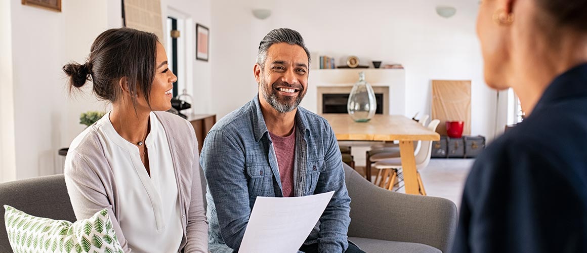 Smiling couple talking with mortgage lender.