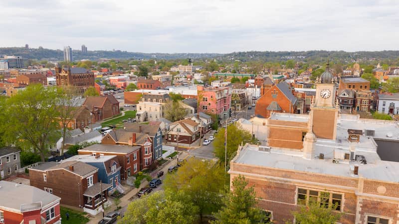 Cloudy skies over quaint downtown Newport, with clocktower, older row homes and trees.