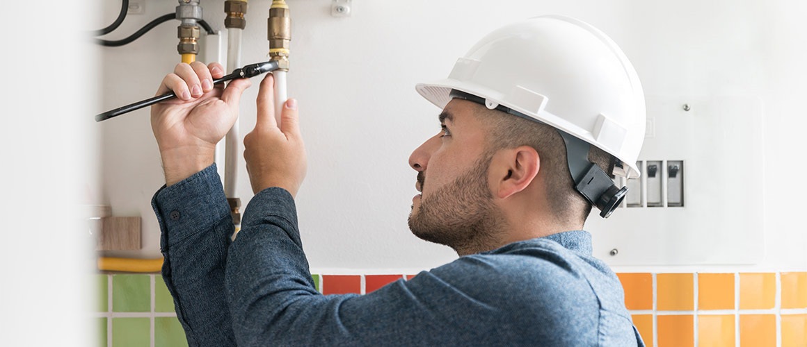 Service technician fixing plumbing in home.
