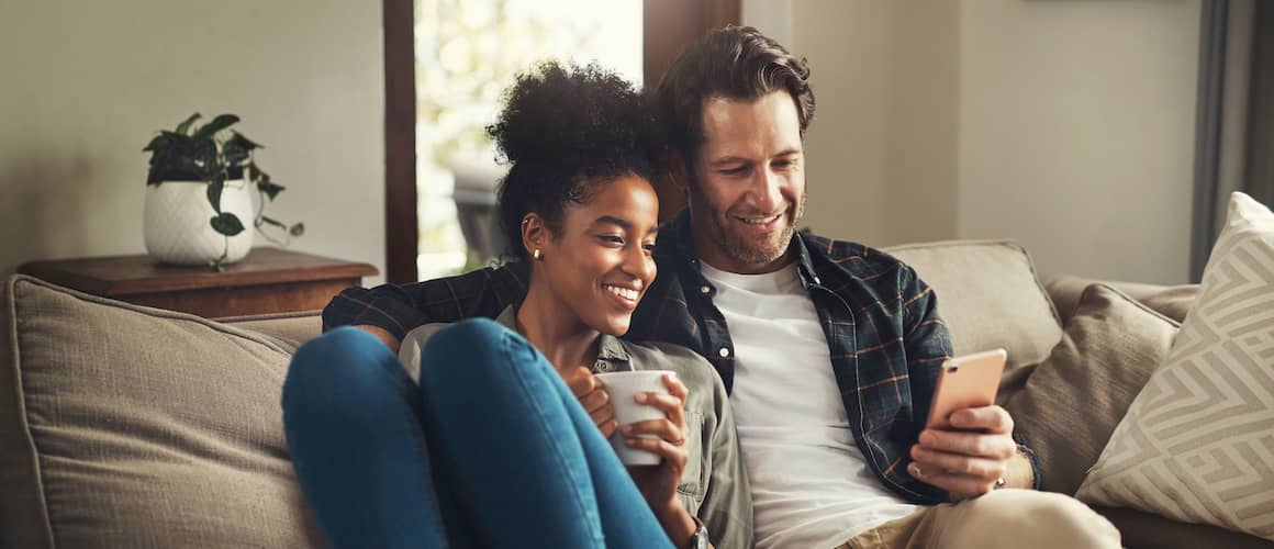 Couple on couch snuggling looking at homes online.