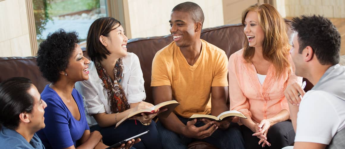 Small group of young adults hanging out together and holding books.