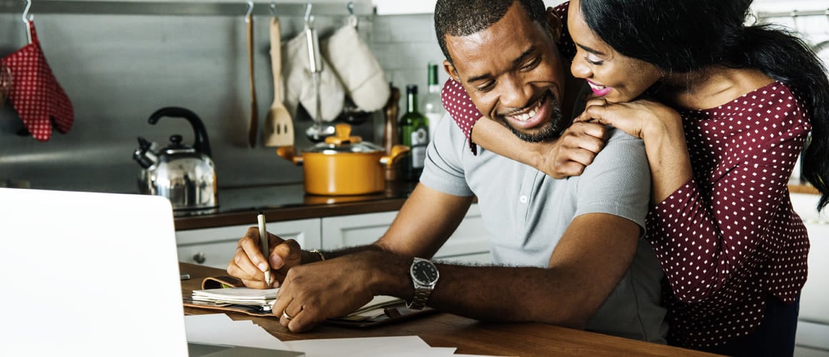 Woman embracing man while working on laptop.