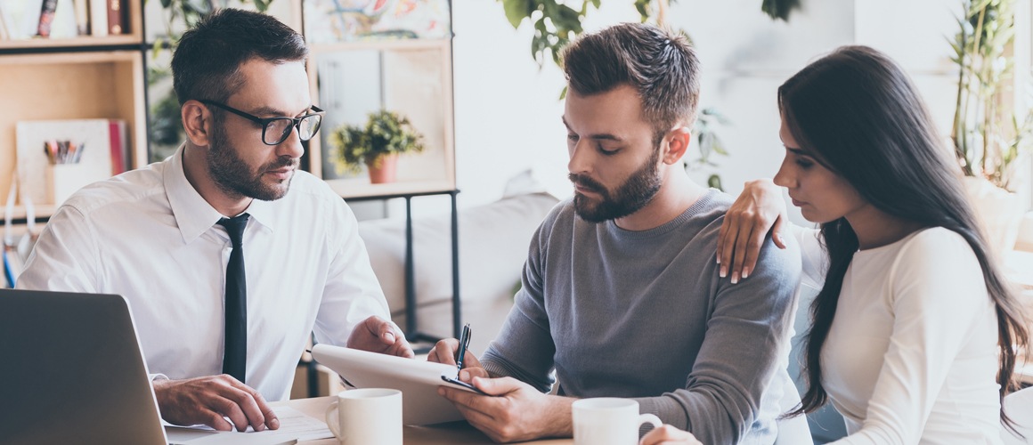 Realtor at desk with couple and paperwork