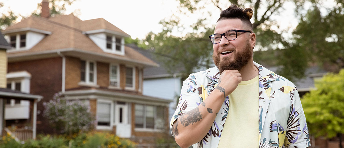 Man with glasses standing in front of house in Detroit.