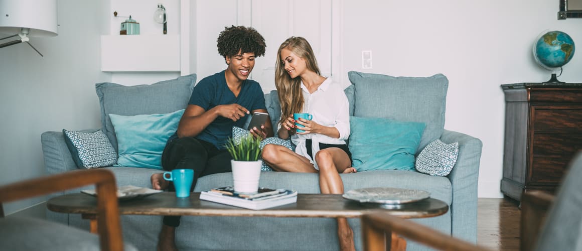 Couple looking at homes online while hanging out on their apartment couch.