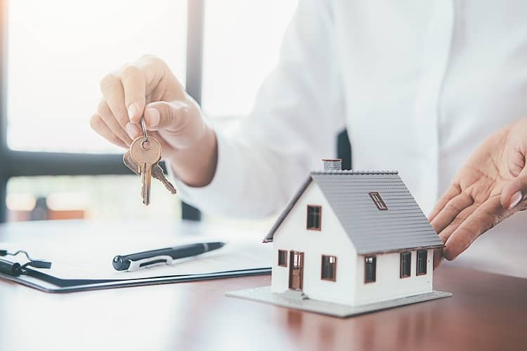 House figurine with paperwork and keys on table