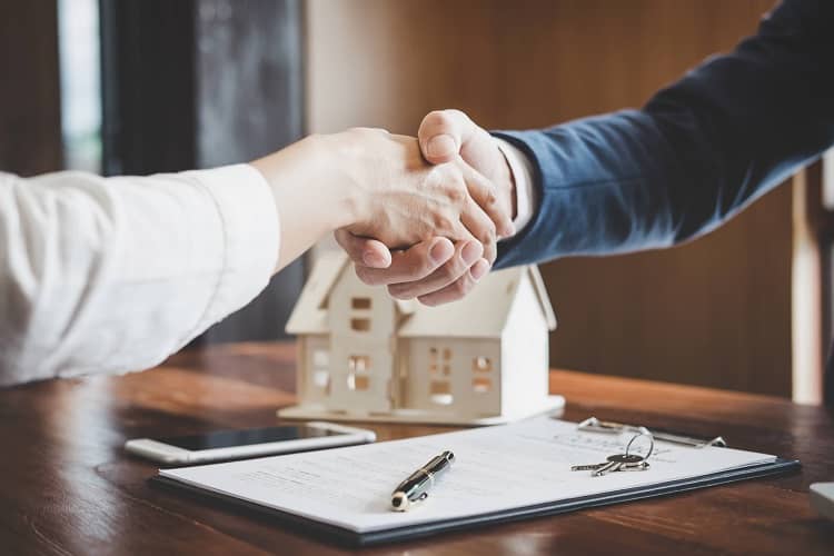 People shaking hands over paperwork