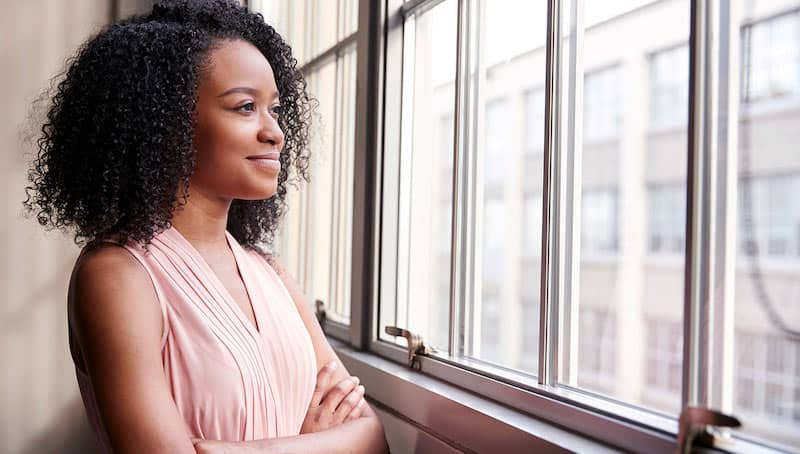 woman crossing arms looking out window