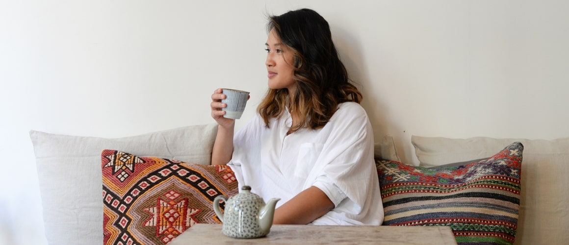 Woman sitting on couch drinking tea.