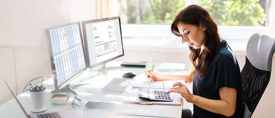 accountant with two monitors and a calculator