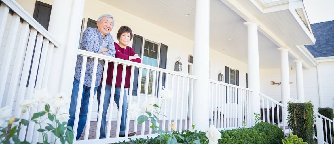 Asian Couple On Front Porch Leaning On Railing