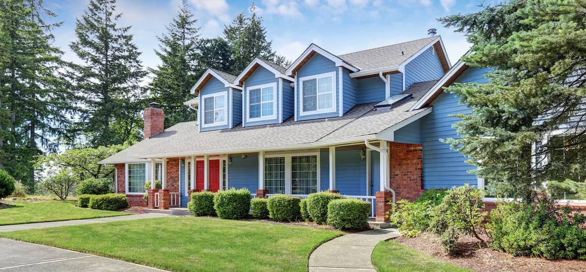 Blue two story house with brick accents and nice green landscaping