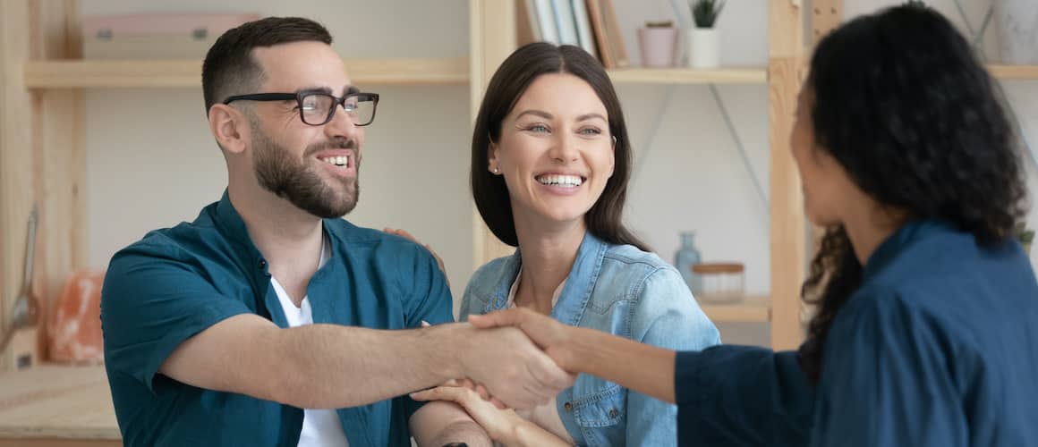 Couple shaking hand with agent.