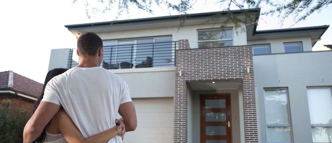 Young couple standing in front of house.