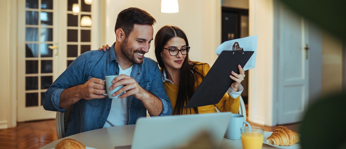 Couple looking at house listings at kitchen table.