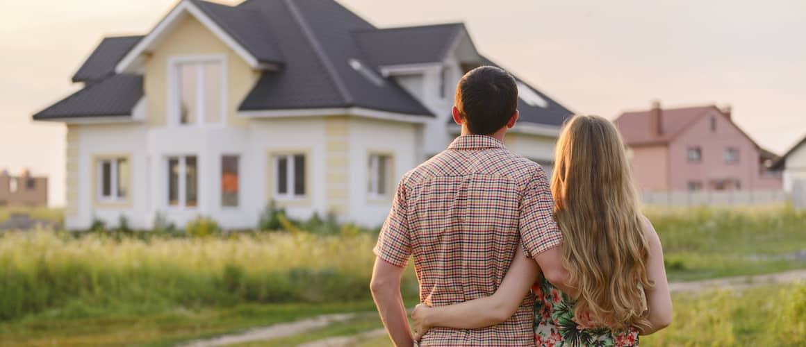 Couple in front of new house at sunset.