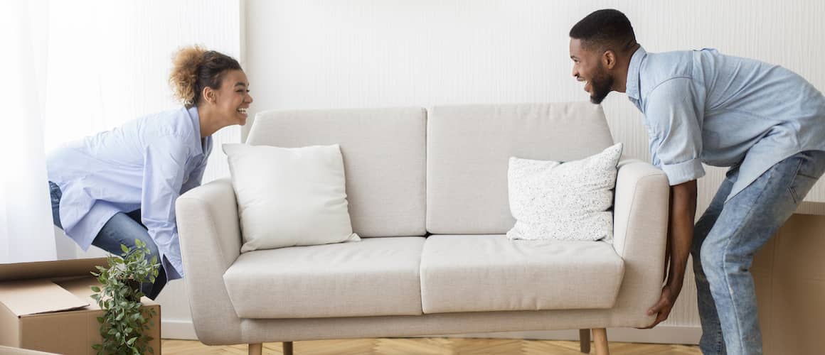 Young couple moving a couch into their new home.
