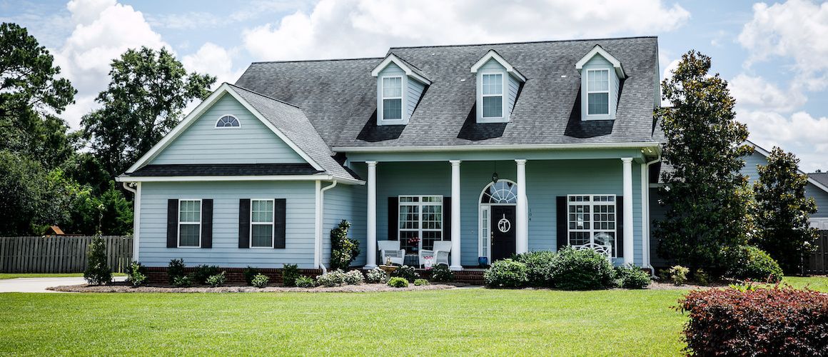 Exterior of light blue suburban home with green grass out front