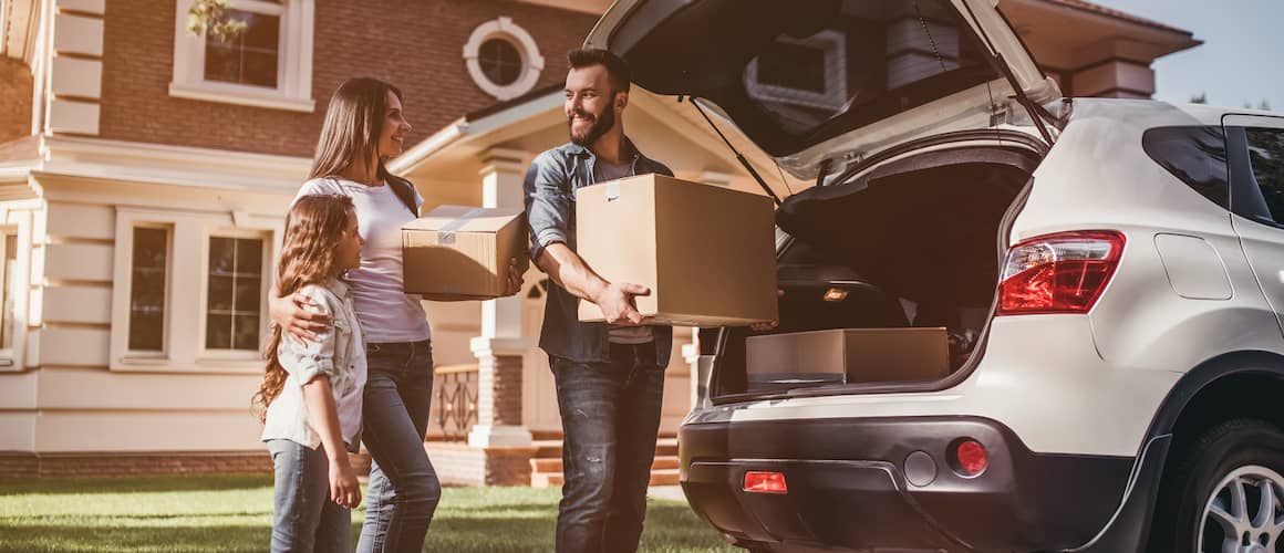 Parents and their daughter packing the back of their car to move homes.