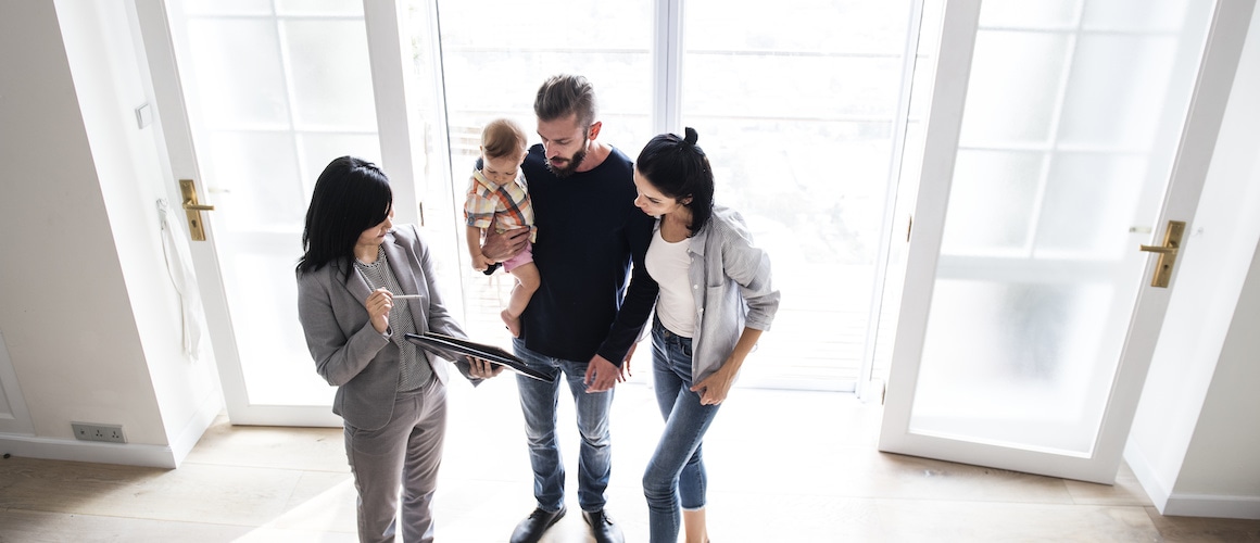 A couple with a baby and their real estate agent touring a new home.