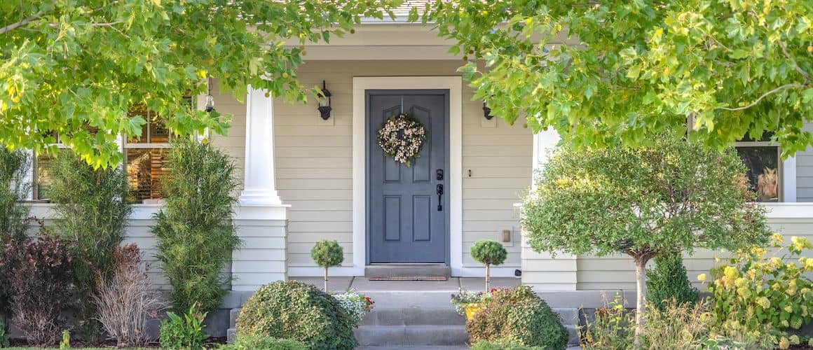 Front door surrounded by green leafy trees.