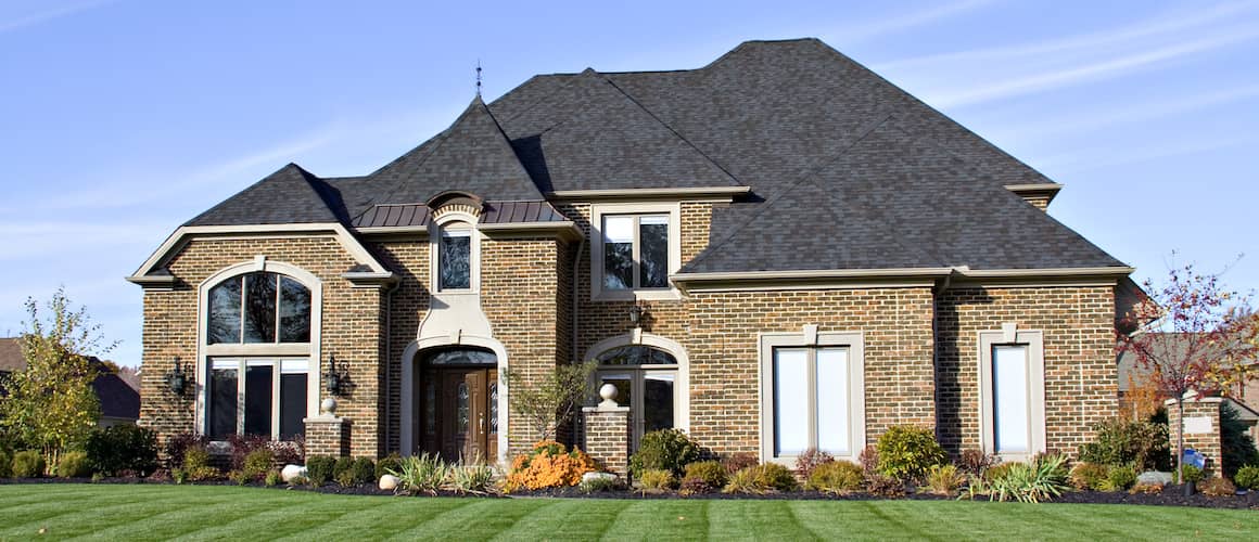 Large Brown Brick House With Black Tall Roof