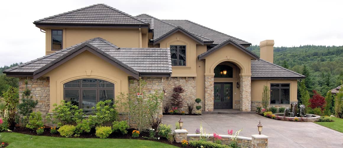 Light Tan Home With Black Roof And Stone driveway