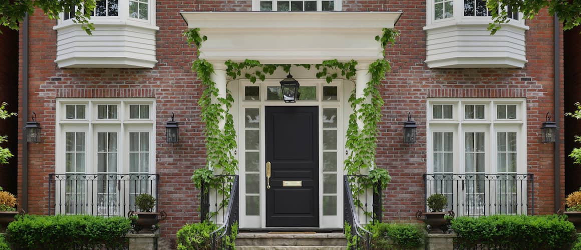 Stately brick home with ivy surrounding porch entryway.