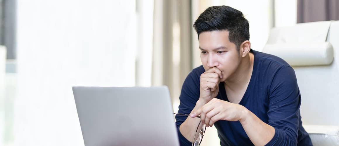 Man looking at laptop concerned and holding glasses
