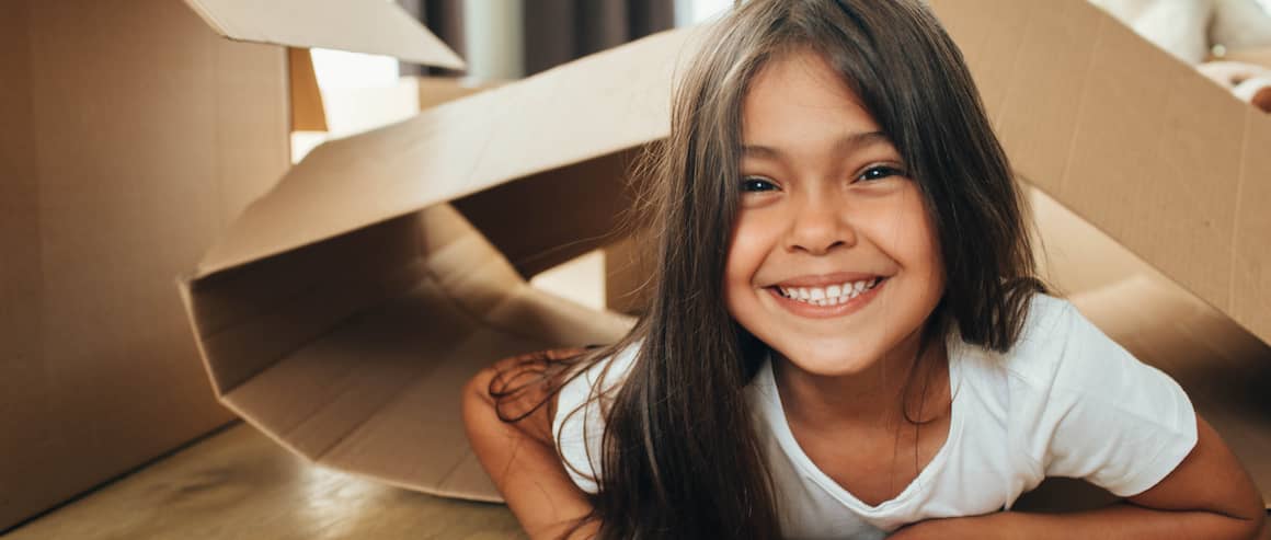 Girl in new home having fun in unpacked boxes.
