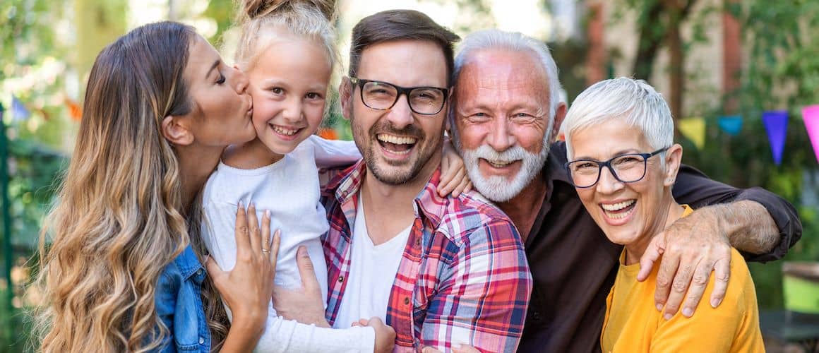 Multiple generations of a family smiling outdoors.