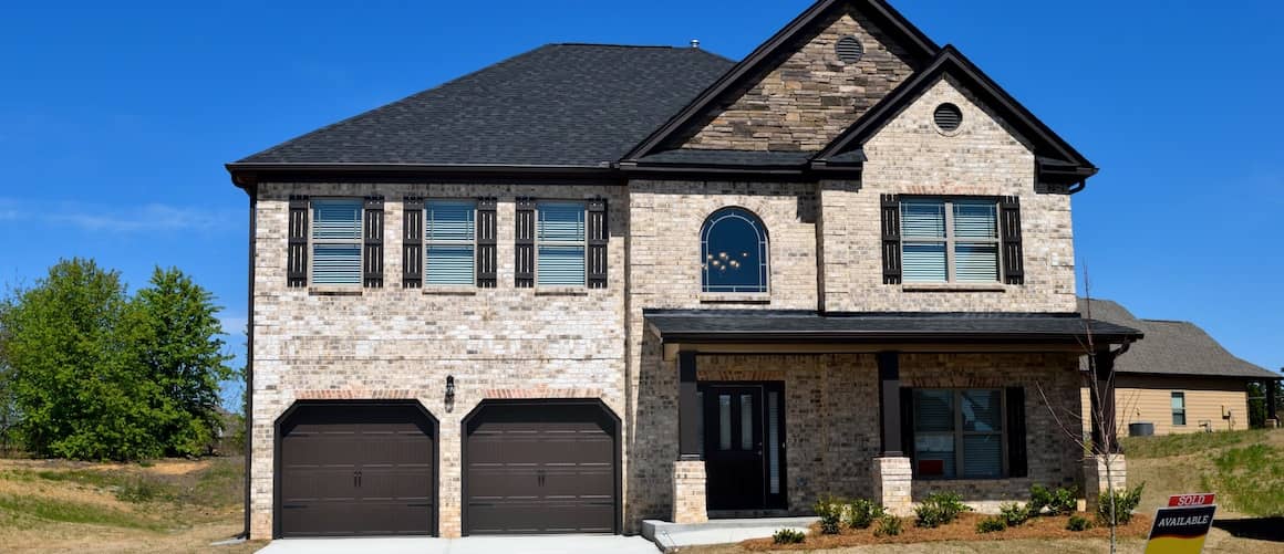 Newly constructed home white bricks with black roof.