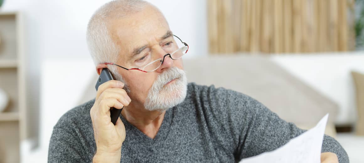 Older man on the phone while looking at bills