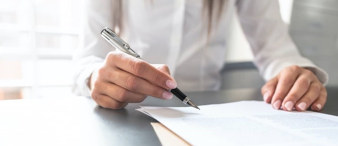 Woman signing purchase agreement with realtor.