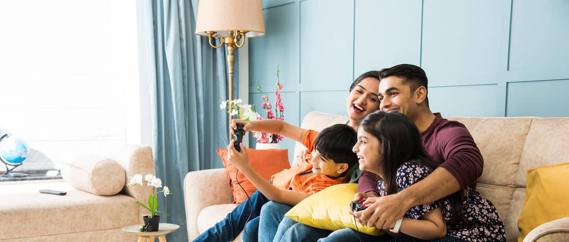 Indian American Family Enjoying Video Games Together In Family Room