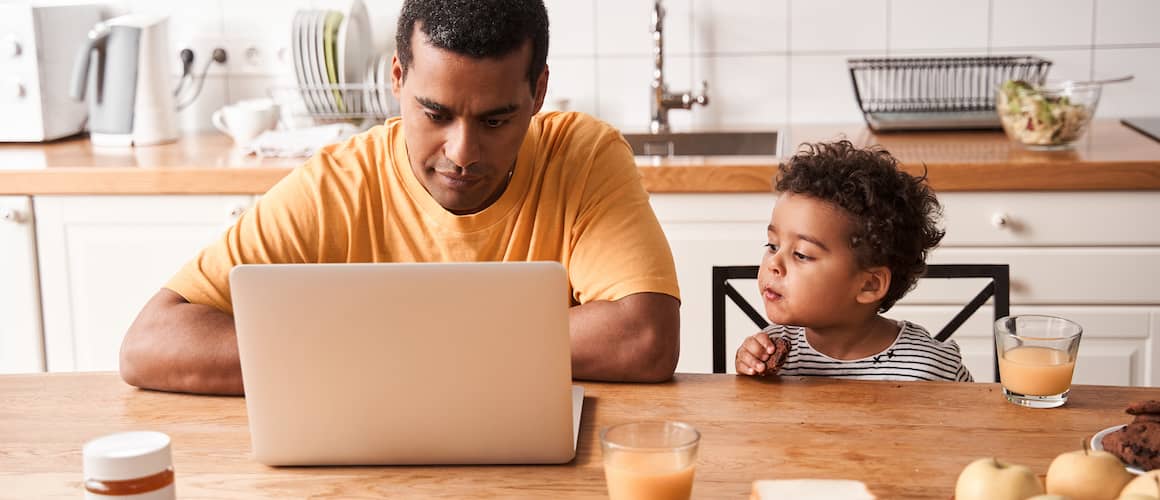 Father and son at kitchen table, father is refinancing and son is looking on.