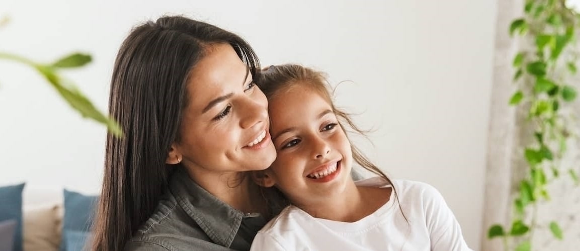 Mother And Daughter Smiling And Snuggling Having Breakfast Together