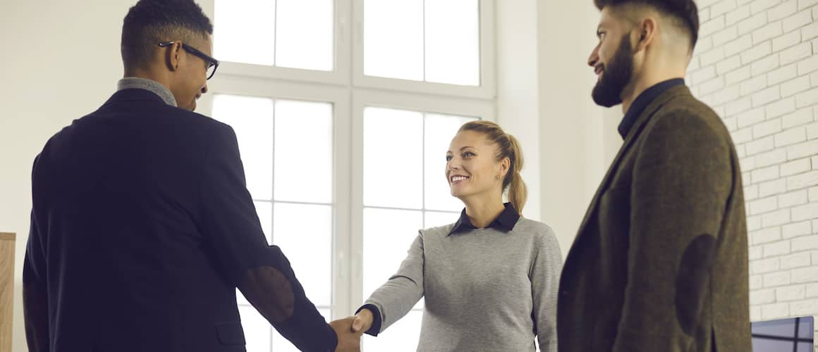 couple shaking hands with agent smiling