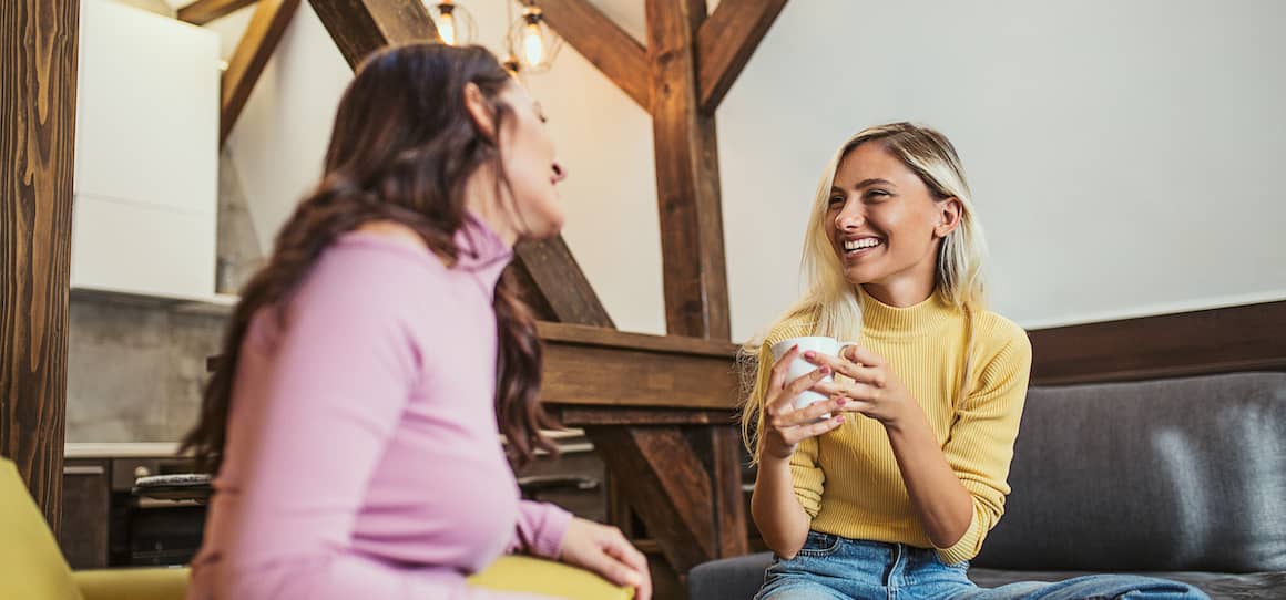 two sisters chatting on couch in a home