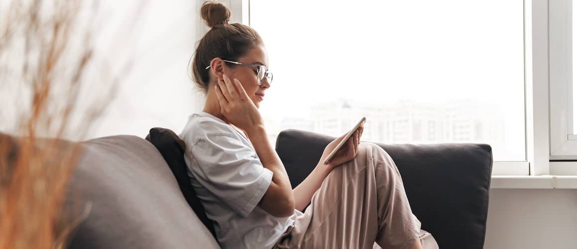 Woman with top knot and comfy clothes reading about mortgages on phone.