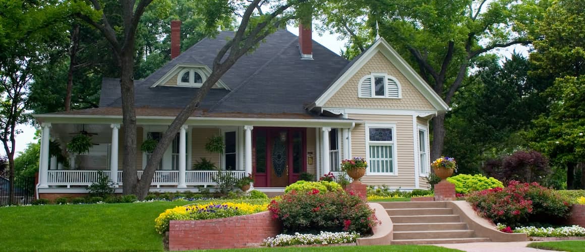 Tan House With Double Layered Front Lawn Brick Steps And A Wrap Around Porch