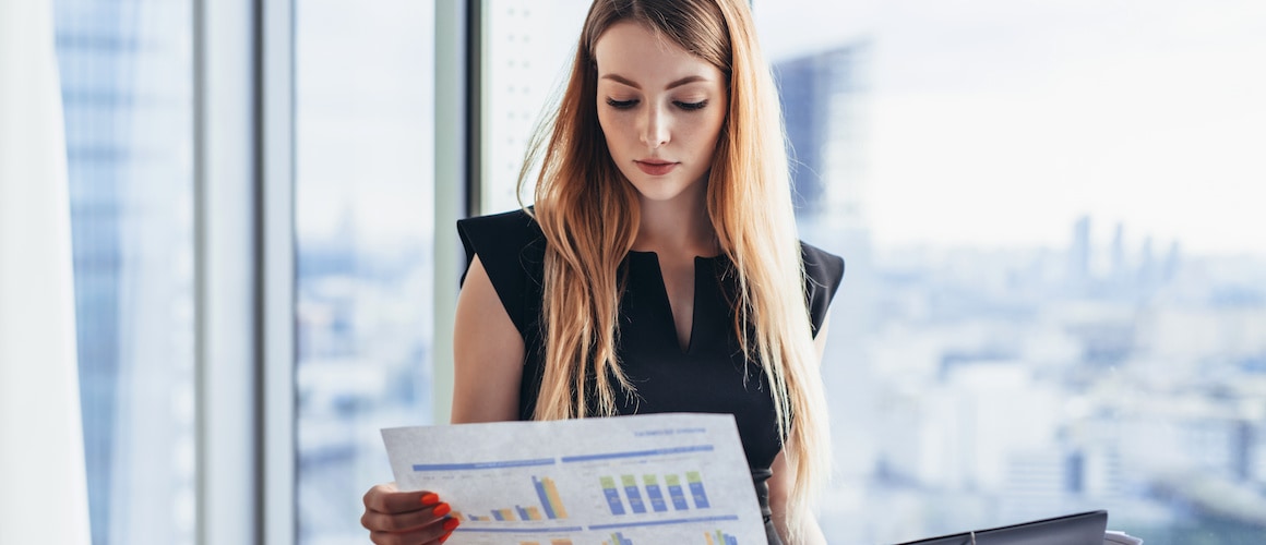 Woman holding paper with bar graphs.