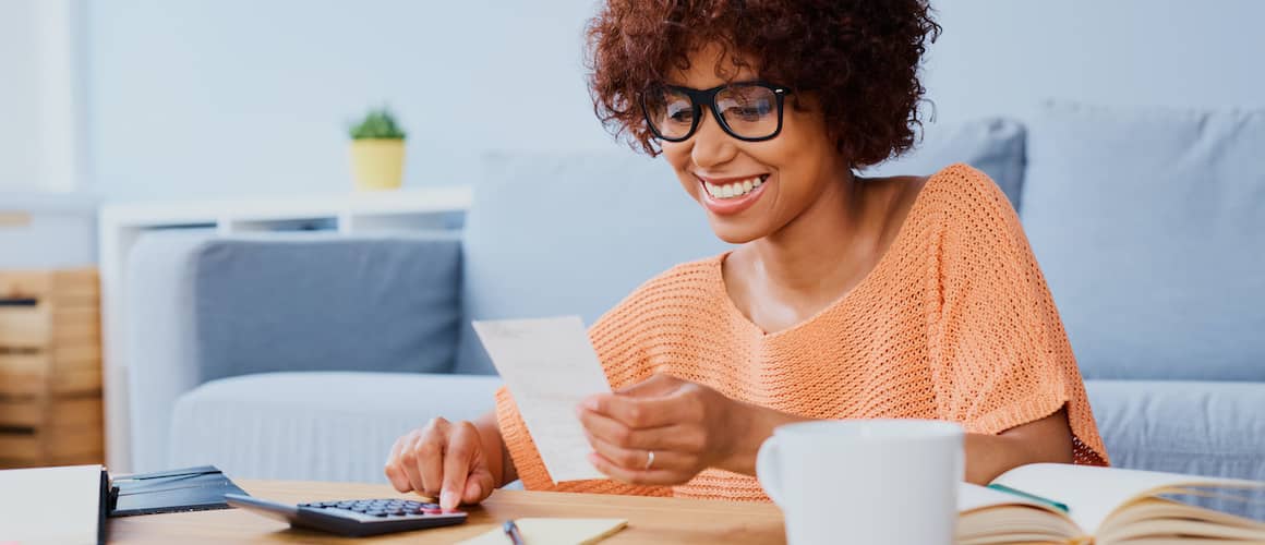 Woman with calculator and paper in peach colored shirt.