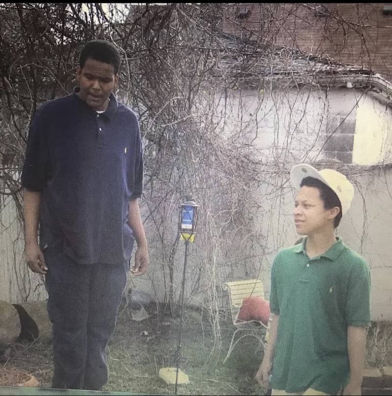 Two young men in front of the wall.