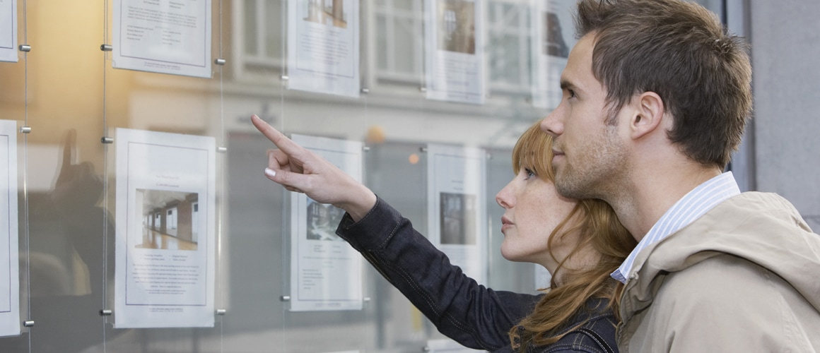 Couple reviewing home listings posted on a wall
