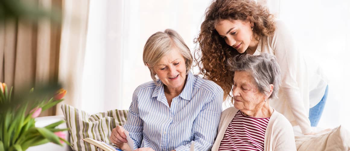 A young girl with her mother and grandmother at home.