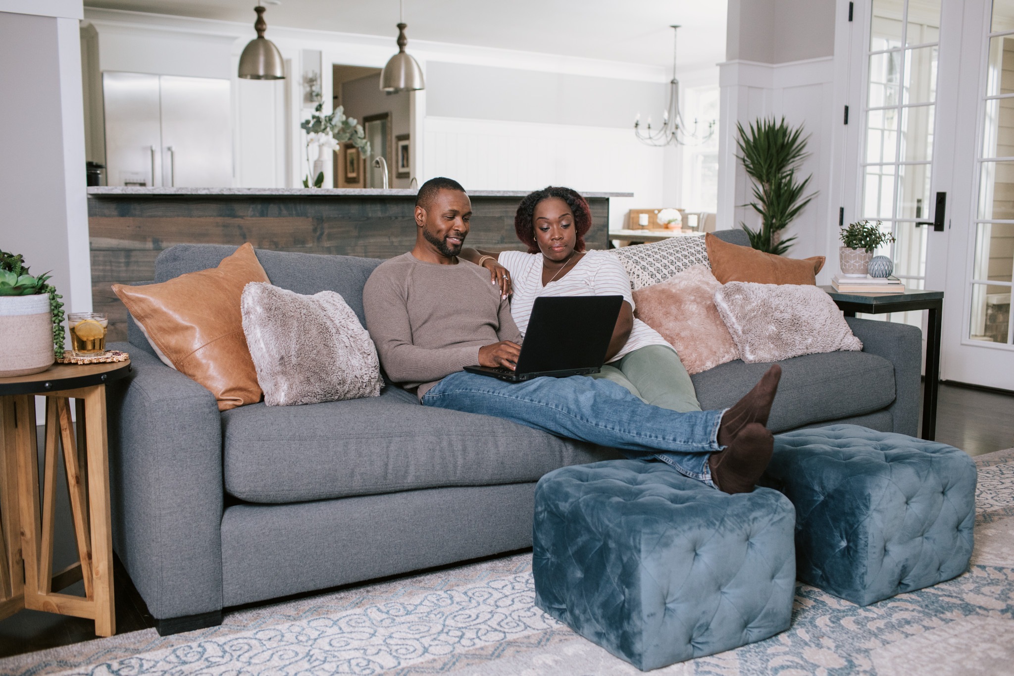 A couple sits together with a laptop on a blue couch.