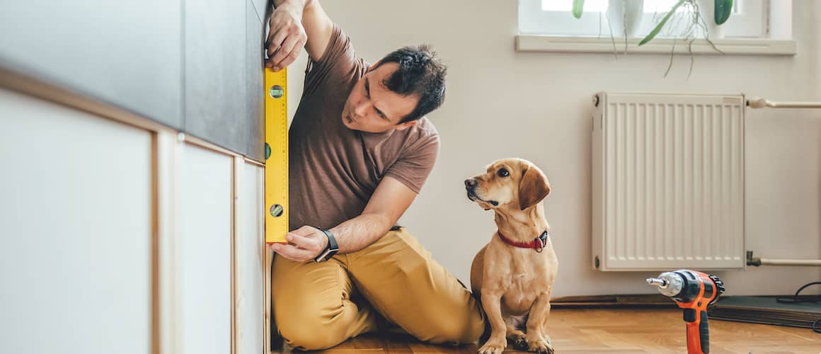 Man works on home renovations while his dog watches.