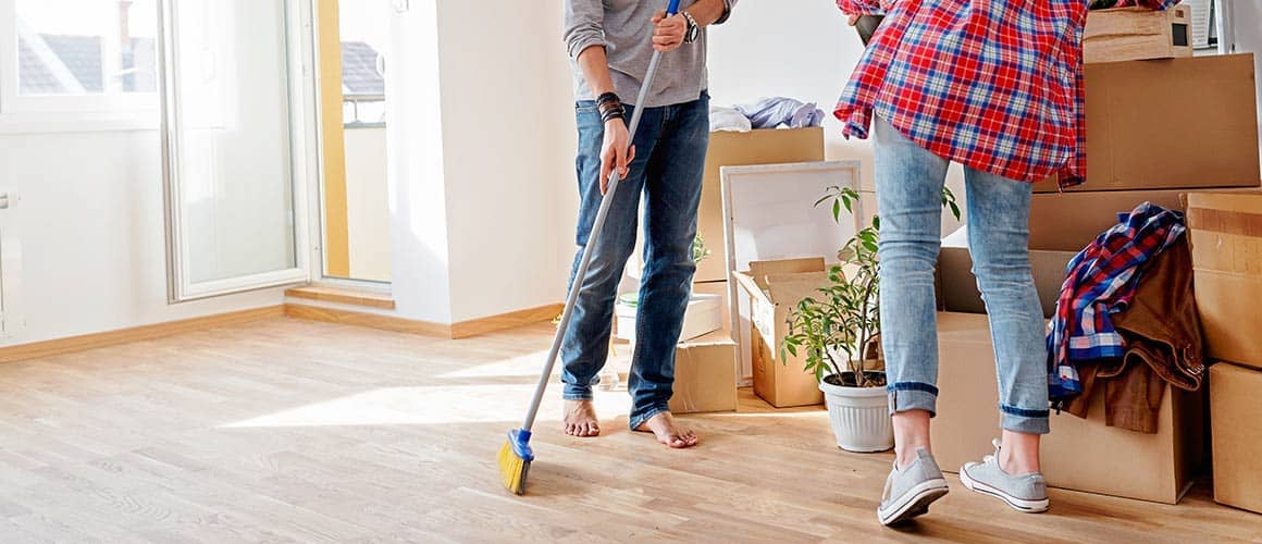 People cleaning room with a room with boxes packed in a corner.